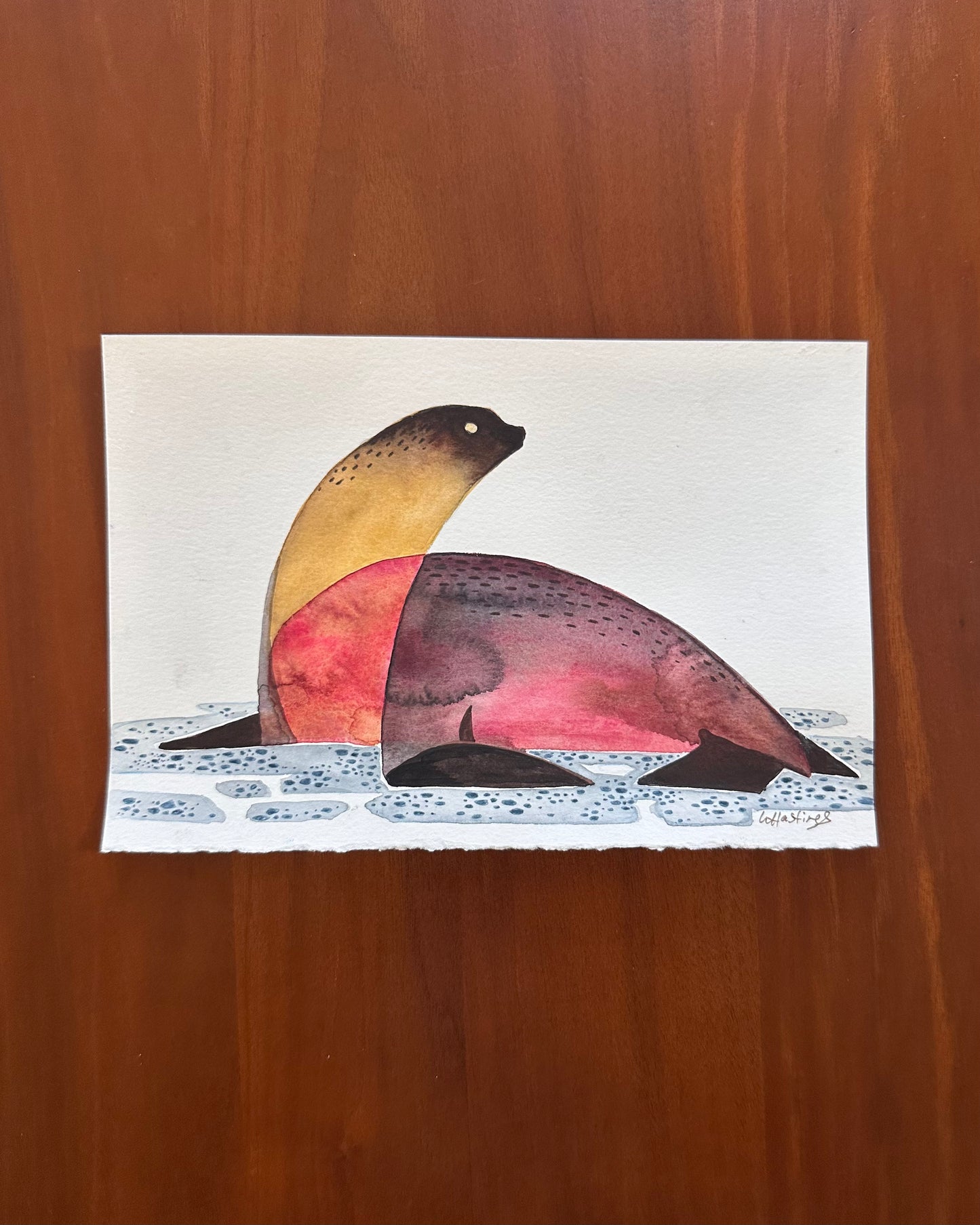 Colorful seal illustration on a white card with a wooden background