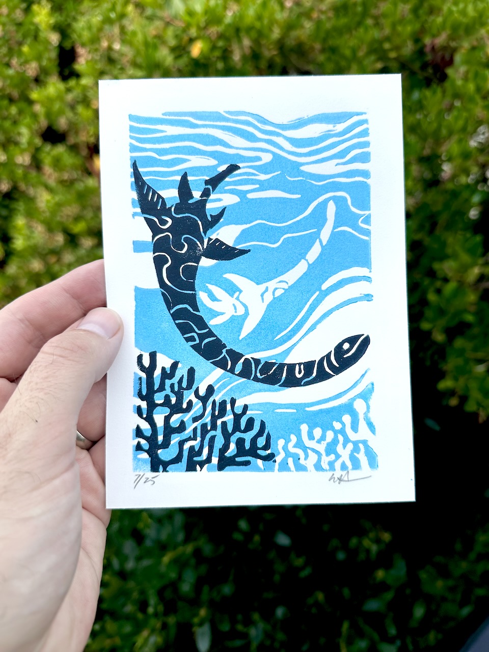 A linocut print of a Plesiosaurus swimming in an oceanic setting with blue and navy colors on fine art paper.