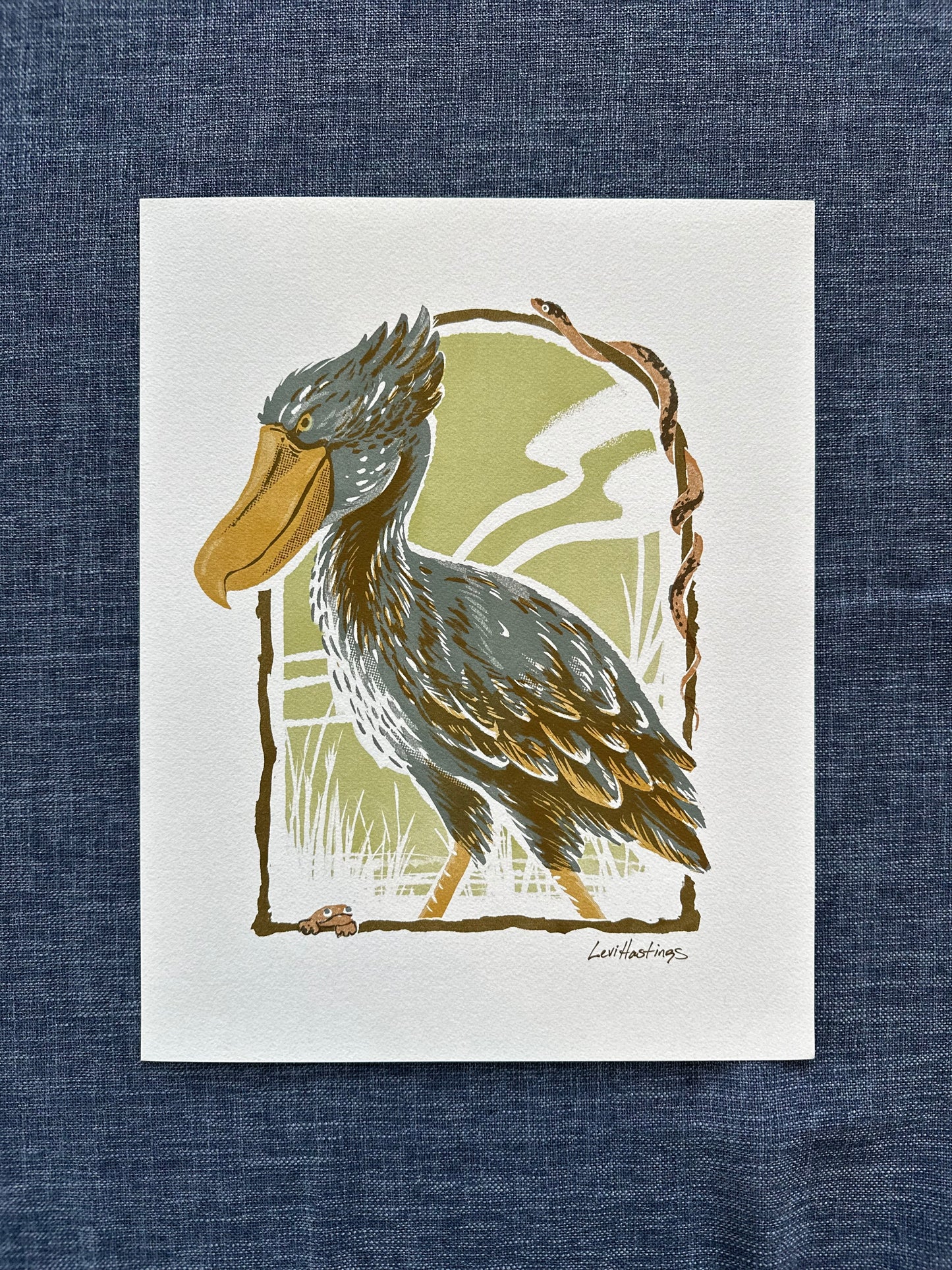 art print featuring  an illustration of a Shoebill Stork, with brown, beige, and gray colors on a green background, framed by a white border.