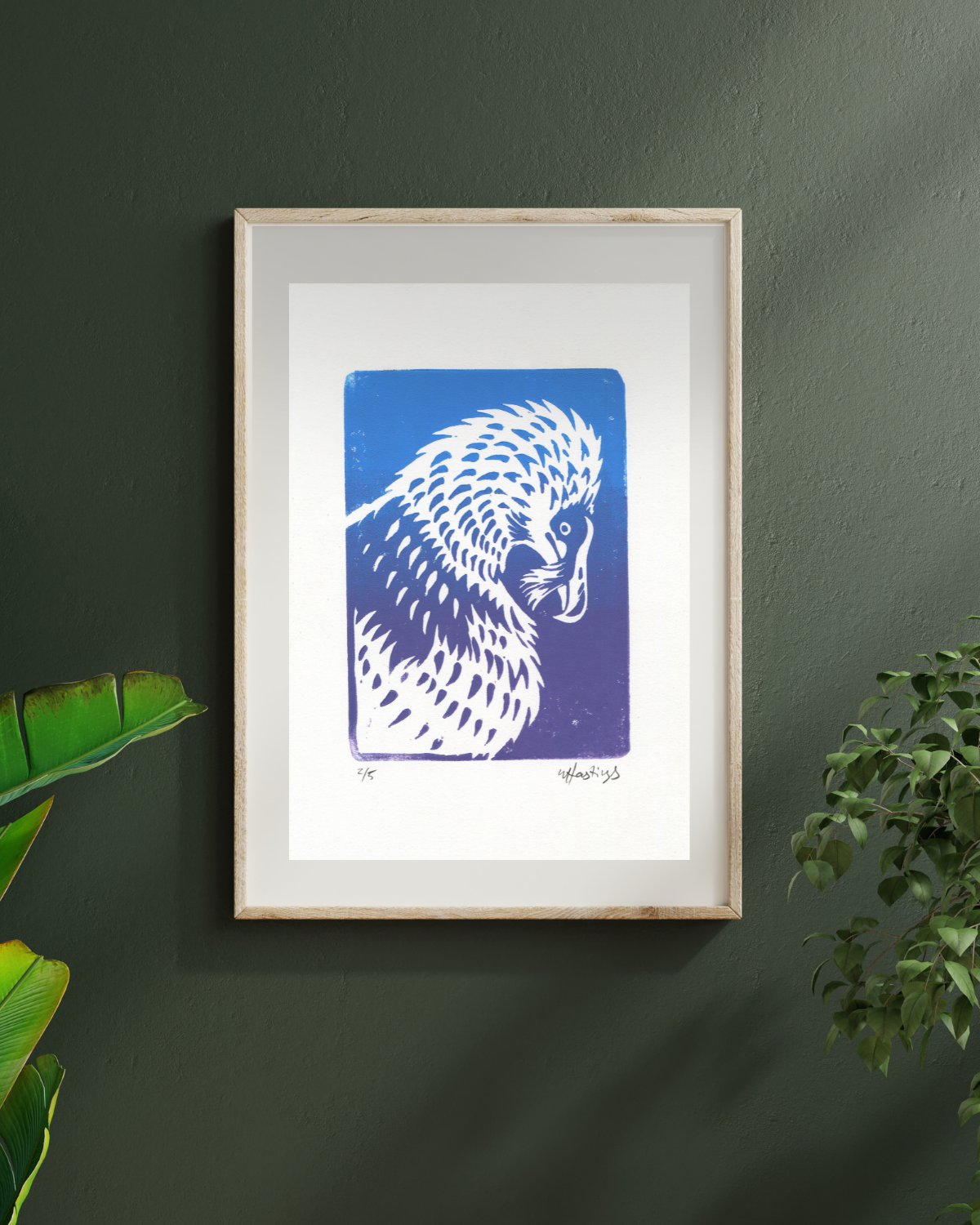 Framed artwork of a blue and white bird on a dark green wall with plants.